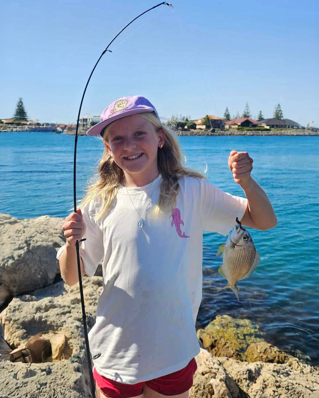 Young girl Milla enjoying fishing during school holidays with her catch