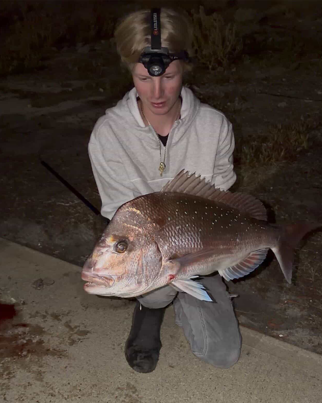 Land-based angler with pink snapper caught from shore